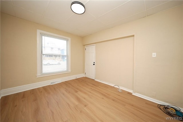 empty room featuring light wood finished floors, visible vents, and baseboards