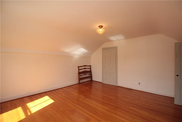 additional living space with vaulted ceiling, baseboards, and wood finished floors