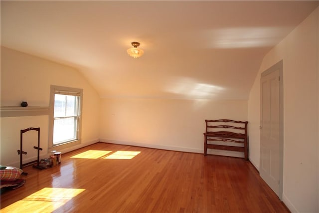 additional living space with baseboards, vaulted ceiling, and wood finished floors