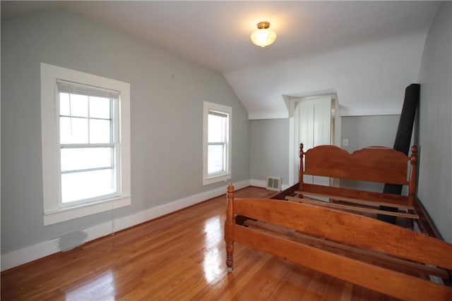 bedroom with vaulted ceiling, wood finished floors, and baseboards