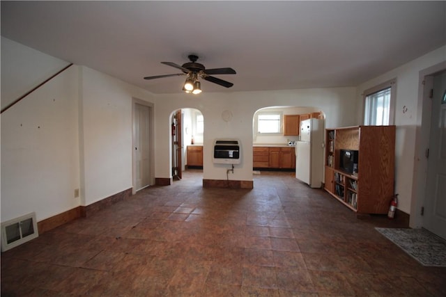 unfurnished living room featuring arched walkways, visible vents, plenty of natural light, and heating unit