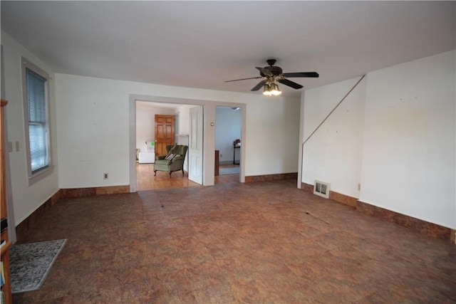 unfurnished living room with baseboards, visible vents, and a ceiling fan