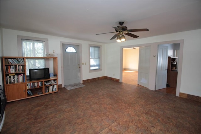 living area featuring plenty of natural light, a ceiling fan, and baseboards