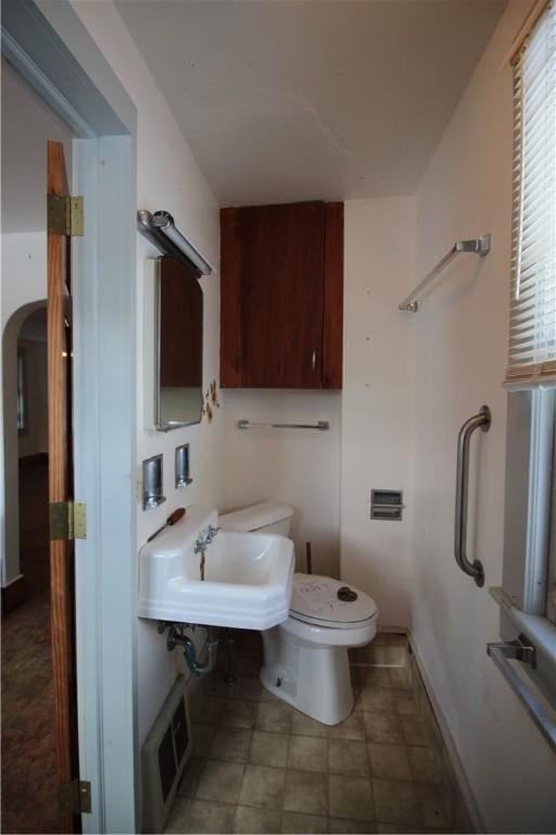 half bath featuring baseboards, visible vents, a sink, and toilet