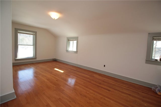 additional living space featuring lofted ceiling, baseboards, and wood finished floors