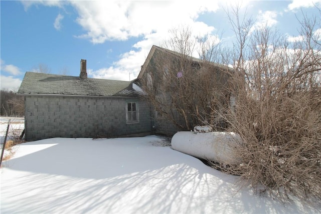 snow covered house featuring roof with shingles