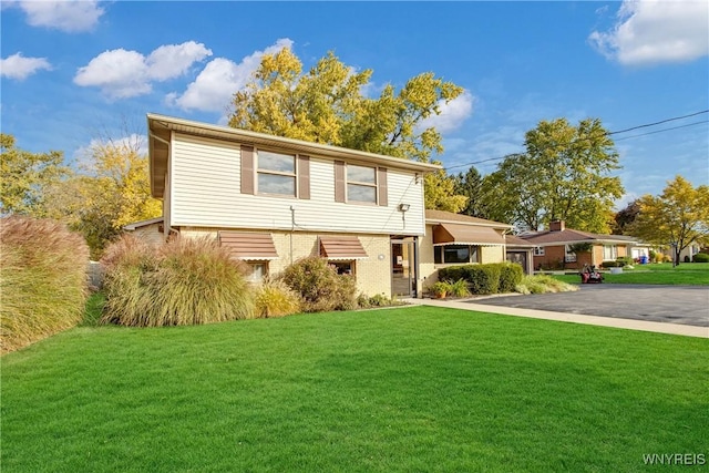 view of front of home featuring brick siding, a front yard, and aphalt driveway