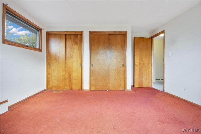 unfurnished bedroom featuring carpet, a baseboard radiator, baseboards, and two closets