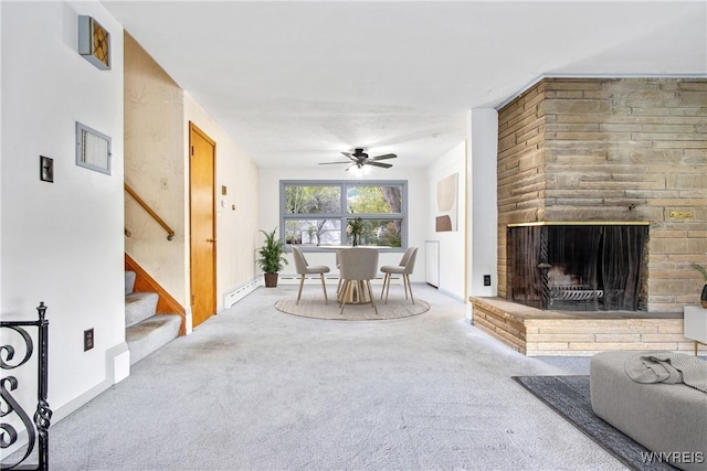 dining space featuring carpet, a fireplace with raised hearth, stairway, a ceiling fan, and baseboards