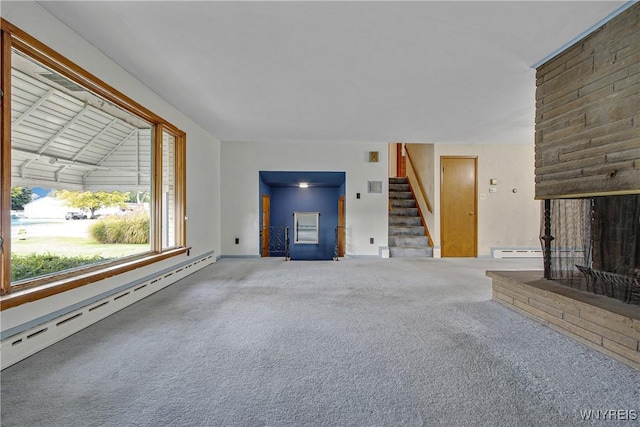 unfurnished living room featuring a baseboard heating unit, carpet, a fireplace, and stairs