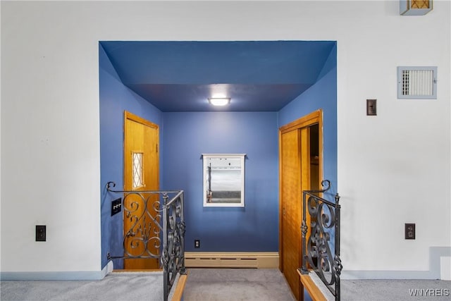 hallway featuring carpet floors, a baseboard radiator, visible vents, an upstairs landing, and baseboards