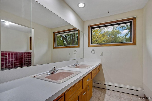 bathroom with double vanity, a baseboard radiator, a sink, and tile patterned floors