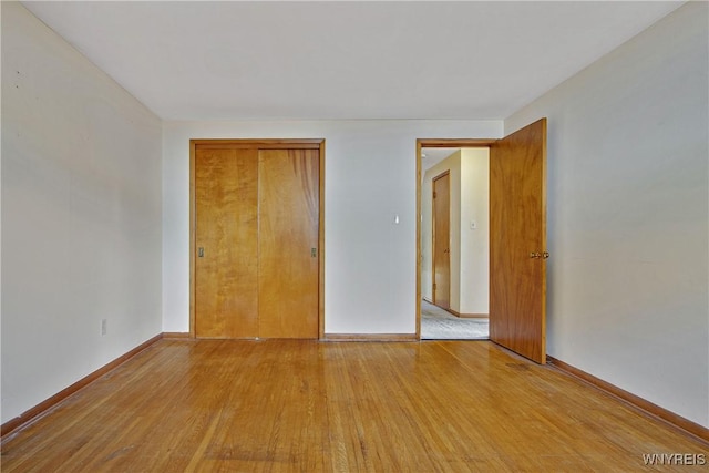 unfurnished bedroom featuring light wood-type flooring, a closet, and baseboards