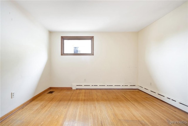 spare room with a baseboard radiator, wood finished floors, visible vents, and baseboards