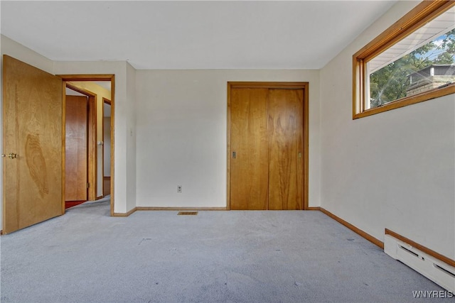 unfurnished bedroom featuring carpet, a closet, a baseboard radiator, and baseboards