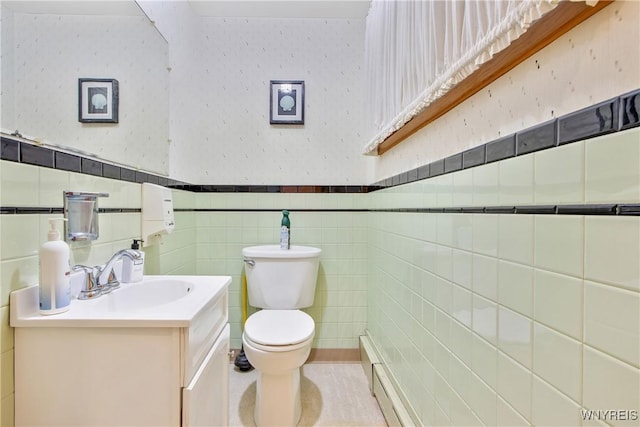 bathroom with toilet, tile walls, vanity, wainscoting, and wallpapered walls