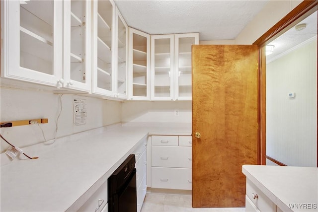 kitchen with white cabinets, glass insert cabinets, light countertops, and a textured ceiling