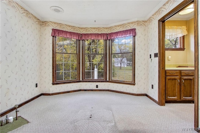 carpeted spare room with wallpapered walls, baseboards, and crown molding