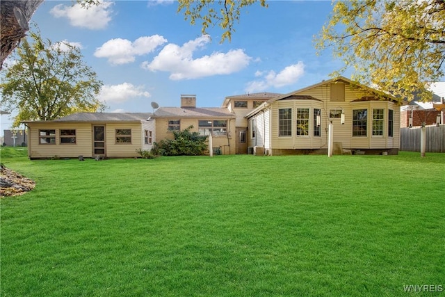 rear view of property featuring a yard and fence