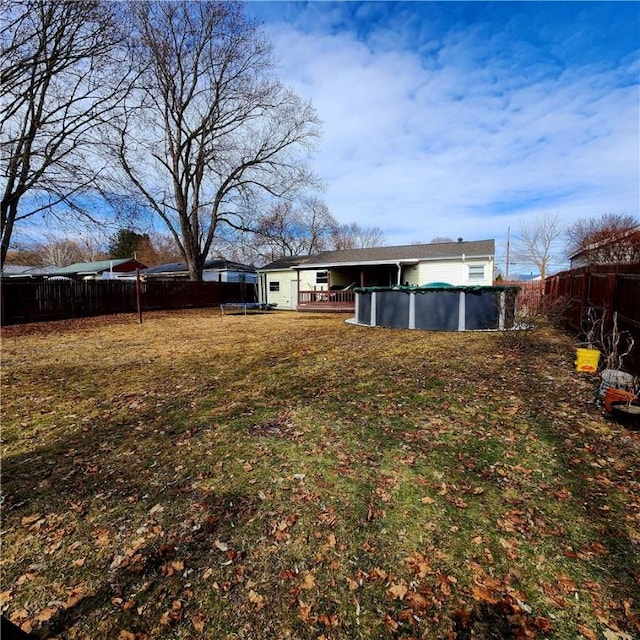 view of yard with a trampoline, a fenced backyard, and an outdoor pool