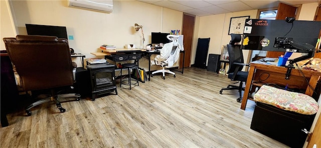 office area featuring an AC wall unit, a drop ceiling, and wood finished floors