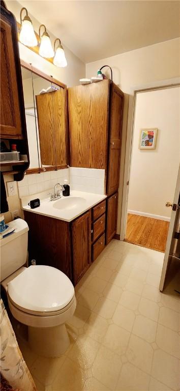 bathroom featuring tasteful backsplash, vanity, and toilet