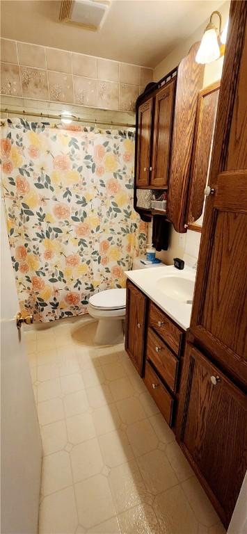 full bathroom featuring curtained shower, visible vents, toilet, vanity, and tile patterned floors