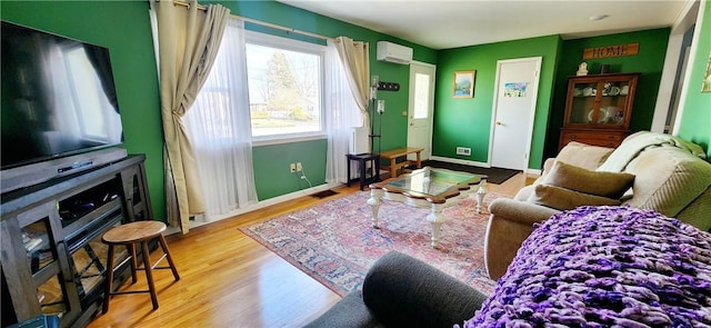 living room with a wall unit AC, visible vents, baseboards, and wood finished floors