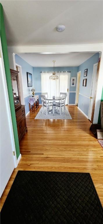 dining space with light wood-style flooring, a chandelier, and baseboards