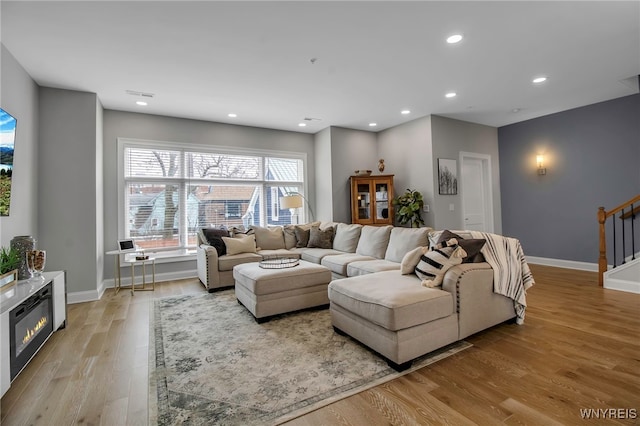 living area with baseboards, visible vents, light wood-style flooring, stairs, and recessed lighting