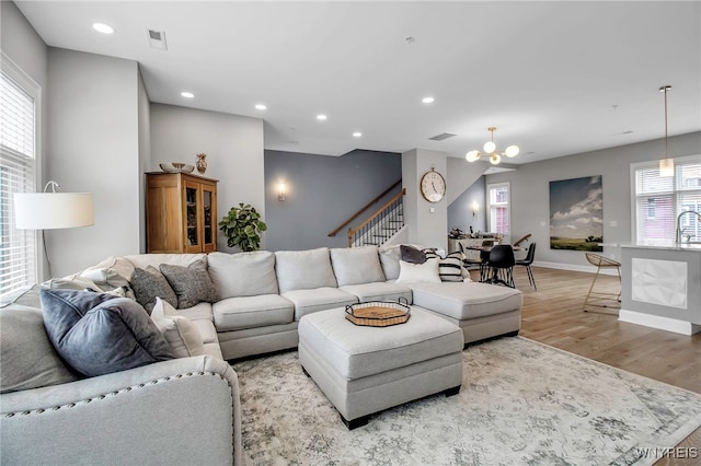 living area featuring light wood-style flooring, recessed lighting, visible vents, baseboards, and stairway