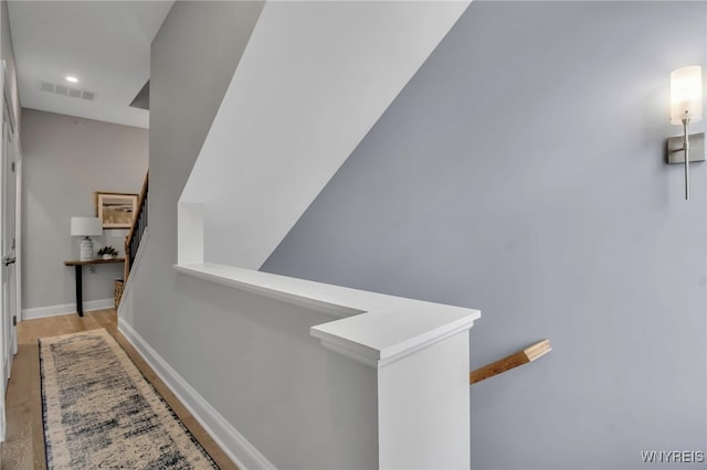 hallway with baseboards, visible vents, wood finished floors, an upstairs landing, and recessed lighting