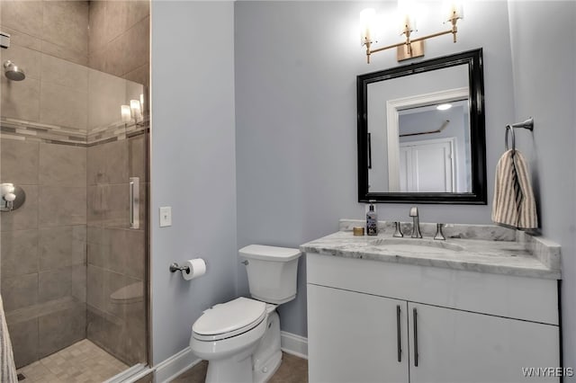 bathroom featuring toilet, a stall shower, baseboards, and vanity