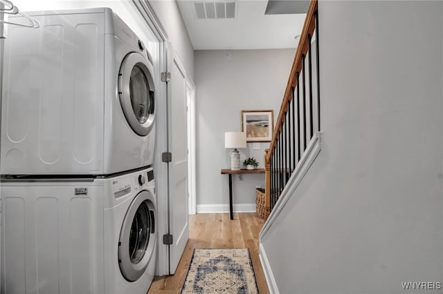 washroom featuring light wood-style flooring, laundry area, visible vents, baseboards, and stacked washer and clothes dryer