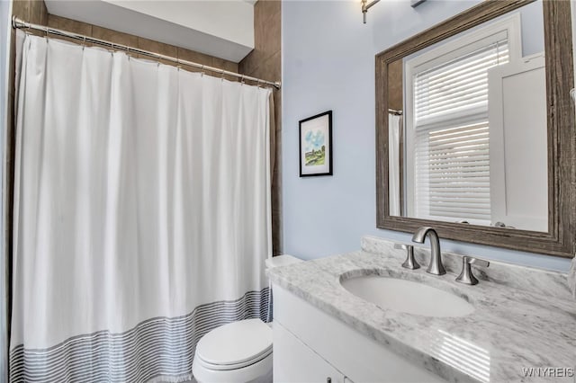 bathroom with curtained shower, vanity, and toilet