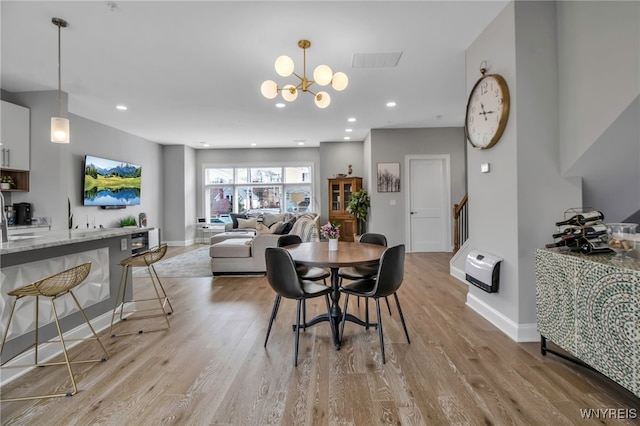 dining space with baseboards, recessed lighting, light wood-type flooring, and an inviting chandelier