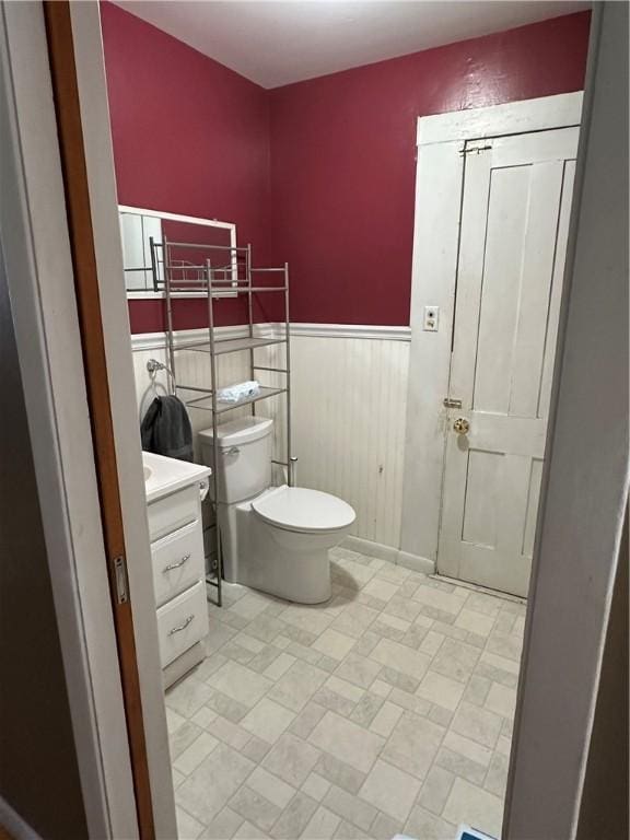 bathroom with wainscoting, vanity, and toilet