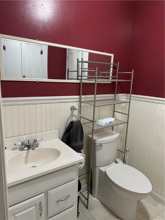 bathroom with toilet, vanity, and wainscoting