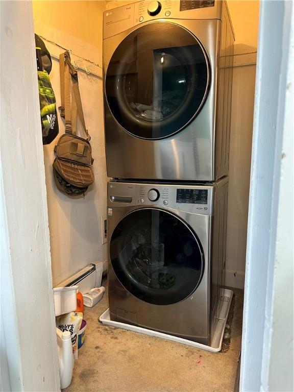 laundry room featuring stacked washer / dryer and baseboard heating