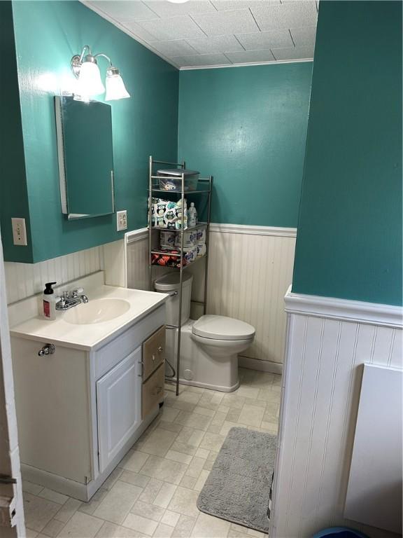 bathroom with a wainscoted wall, toilet, and vanity