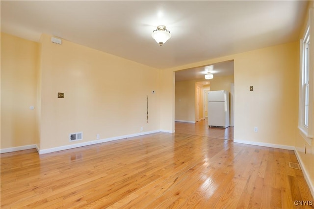 spare room featuring light wood-style flooring, visible vents, and baseboards