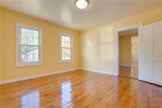 unfurnished room with light wood-style flooring and baseboards