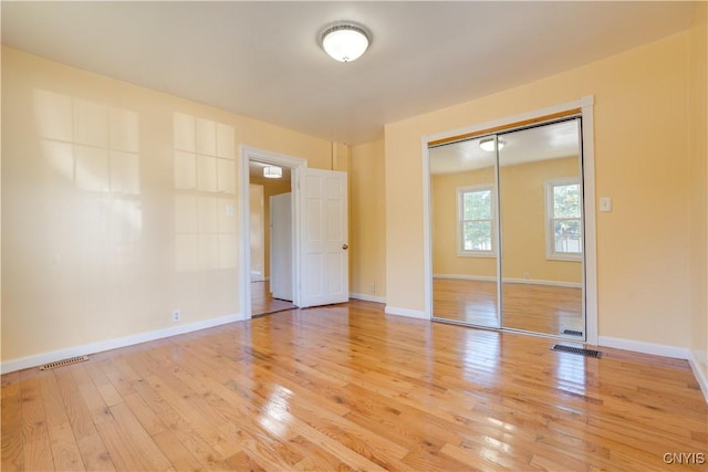 unfurnished bedroom with light wood-style floors, baseboards, visible vents, and a closet