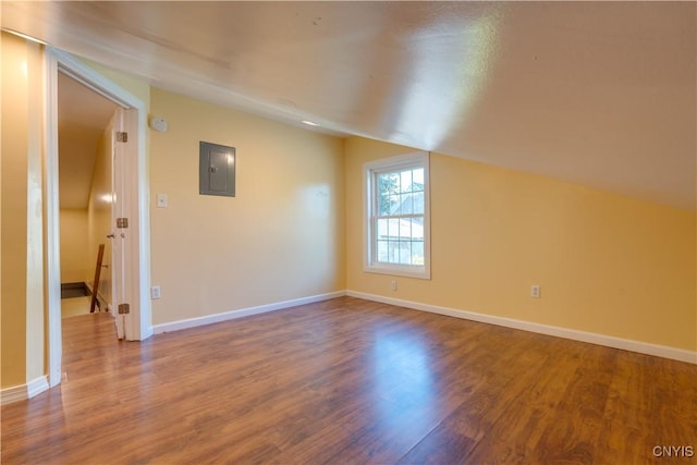 bonus room featuring lofted ceiling, electric panel, baseboards, and wood finished floors