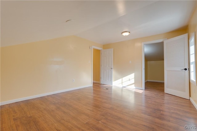 empty room with lofted ceiling, wood finished floors, and baseboards