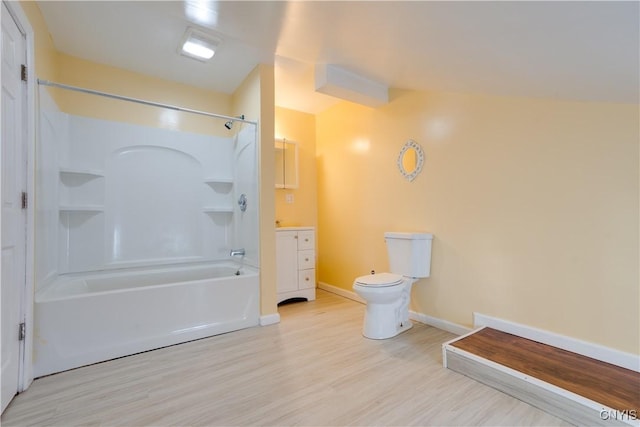 bathroom featuring baseboards, bathing tub / shower combination, toilet, wood finished floors, and vanity