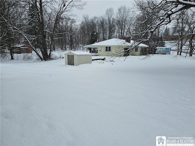 yard layered in snow with a storage shed and an outdoor structure