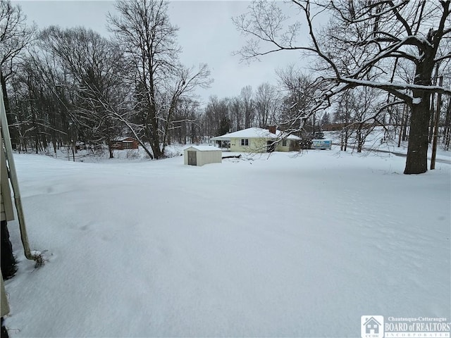 snowy yard featuring an outbuilding and a shed