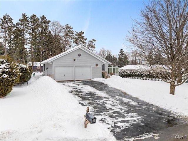 view of snowy exterior featuring aphalt driveway and an attached garage