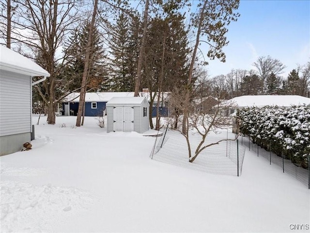 yard layered in snow featuring a storage shed and an outbuilding